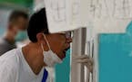 A resident gets his routine throat swabs at a COVID-19 testing site in Beijing, Sunday, Aug. 7, 2022. Another 259 COVID-19 cases have been reported in