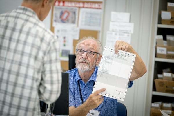 Election judge Bob Lewis explained how to fill out a ballot to a voter at the Minneapolis early voting center on Wednesday.