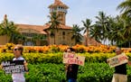People protesting against former President Donald Trump hold signs near his Mar-a-Lago residence in Palm Beach, Fla., on Aug. 9. An FBI search of the 