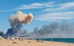 Rising smoke can be seen from the beach at Saky after explosions were heard from the direction of a Russian military airbase near Novofedorivka, Crime
