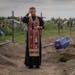 A priest prays for unidentified civilians killed by Russian troops during Russian occupation in Bucha, on the outskirts of Kyiv, Ukraine, Thursday, Au