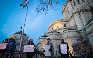 People held signs during a December 2020 rally and vigil in St. Paul to honor and memorialize those who have died of COVID-19 while incarcerated.