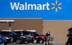 FILE - A woman wheels a cart with her purchases out of a Walmart, on Nov. 18, 2020, in Derry, N.H. Walmart Inc. on Tuesday, Aug. 16, 2022, reported fi