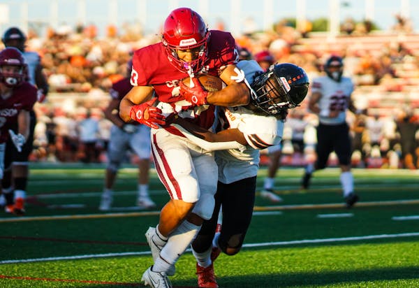 Maple Grove running back Jordan Olagbaju fought off two Osseo defenders in scoring his team’s first touchdown of the season. 