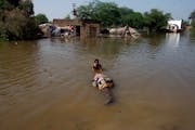 A man carries salvageable belongings from his flood-hit home in Shikarpur district of Sindh province, of Pakistan, Wednesday, Aug. 31, 2022.