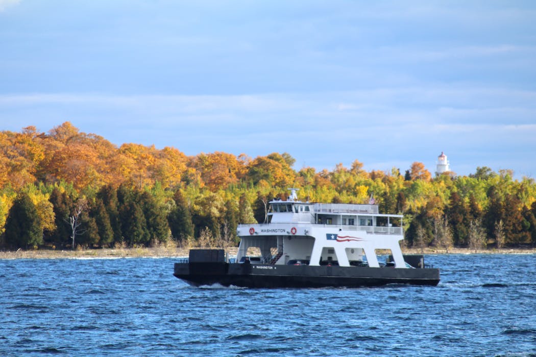 The Washington Island Ferry sails through the Death's Door water passage and passes by Plum Island and the Plum Island Rangelights on a fall day in Door County, Wisconsin.