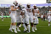 Minnesota players celebrate with Daniel Jackson, center, after his touchdown against Michigan State during the first quarter of an NCAA college footba