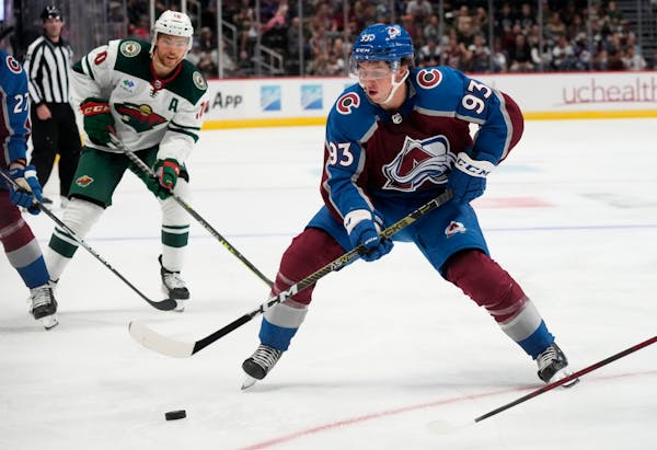 Colorado Avalanche center Jean-Luc Foudy, front, collects the puck as Minnesota Wild center Tyson Jost pursues on Tuesday.