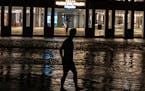 A man walks through a flooded street in front of a hotel powered by an oil generator during a blackout in Havana, Cuba, Wednesday, Sept. 28, 2022. Cub