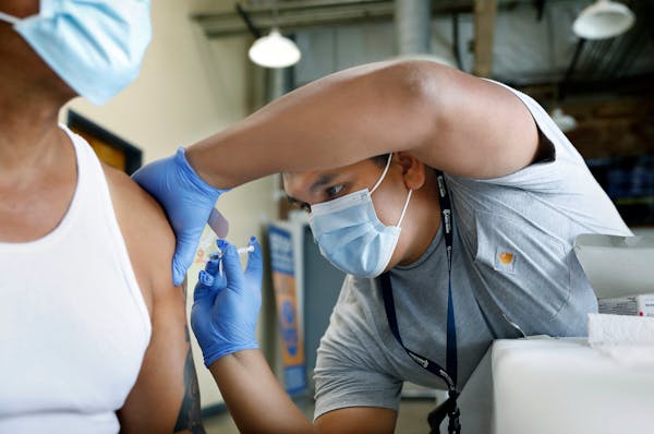 Jeremy Oyague, right, a registered nurse with the Los Angeles County Department of Public Health, administered a COVID-19 vaccine booster during a cli