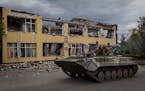 Ukrainian soldiers ride past a destroyed building in the town of Kupiansk, Ukraine, on Tuesday, Sept. 20, 2022. After stunning battlefield setbacks, R
