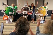 Club members pose with 4-foot-tall figures they won at auction during the 24th Annual M&M’s Collectors Club Convention on Wednesday at the Embassy S