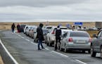 People walk next to their cars queuing to cross the border into Kazakhstan about 250 miles south of Chelyabinsk, Russia, on Tuesday. Officials say abo