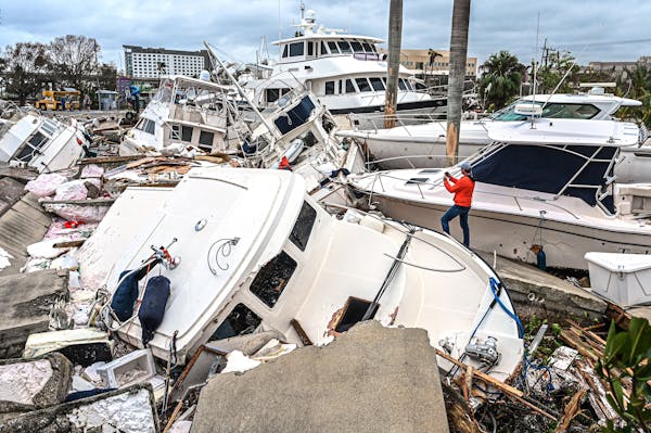A man took photos of boats damaged by Hurricane Ian in Fort Myers, Fla., on Thursday.