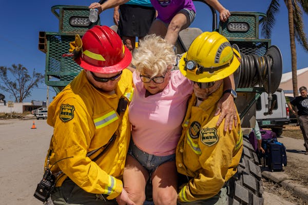 Diana Kauth was helped off a rescue rig by Florida Forest Service firefighters after riding out Hurricane Ian inside her neighbor’s two-story home o