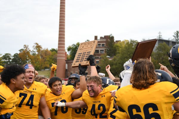 Carleton football players celebrated with their Book of Knowledge trophy after beating Macalester on Saturday in Northfield.