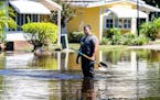 A Seminole County firefighter works to clear a drain at an intersection in Hacienda Village, a 55-plus manufactured homes community in Winter Springs,