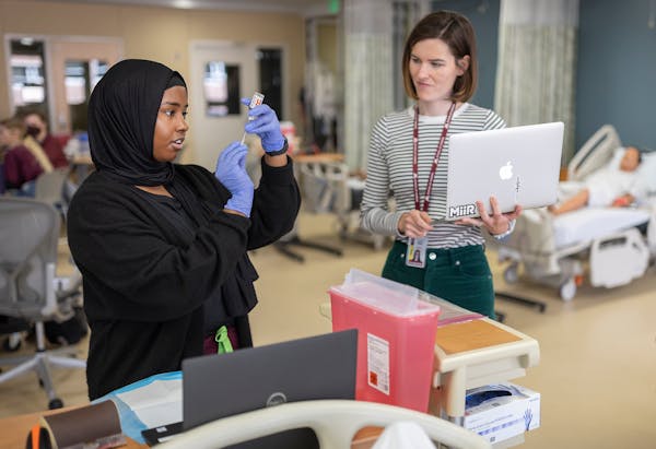 Nursing student Ruqiya Warsame, left, practices drawing insulin under the watchful eye of instructor Laura Mullin, right, at the University of Minneso
