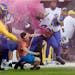 A fan with a smoke bomb is tackled on the field by Los Angeles Rams’ Bobby Wagner, (45), Takkarist McKinley (50) and a security guard during their N