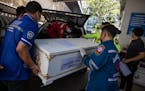 Volunteer workers load a coffin into an ambulance at the hospital in Udon Thani, Thailand after a mass shooting at a nearby nearby child care center l