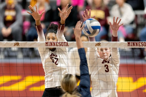 Minnesota’s Carter Booth (52), left, and McKenna Wucherer (3) block at the net against Illinois earlier this season.