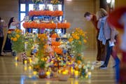 Artist Monica Vega, left, placed a photo on the first-ever “Altar de Muertos” or community altar, for Days of the Dead at the Minnesota State Capi
