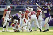 Cardinals quarterback Kyler Murray stayed on the ground after a sack by Vikings edge rusher Za’Darius Smith, right, on Sunday.