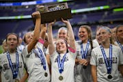 Holy Angels player celebrate with their trophy after defeating Mahtomedi in the girls' Class 2A soccer state championship gam.
