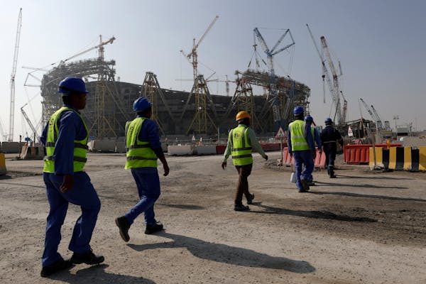 Workers walk to the Lusail Stadium, one of the 2022 World Cup stadiums, in Lusail, Qatar, Friday, Dec. 20, 2019. Migrant laborers who built Qatar’s 