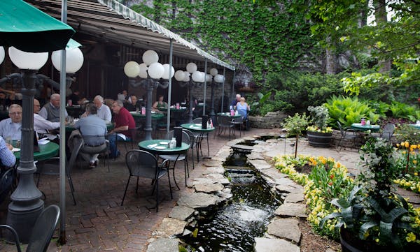 Jax Cafe in northeast Minneapolis. A patio garden, with a stream, a water wheel, flowers, a tented seating area. [ Sidewalks Cafe’s Photos by Rick N