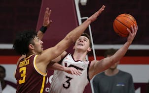 Virginia Tech’s Sean Pedulla scored from underneath the basket while being guarded by Gophers forward Dawson Garcia in the first half Monday.
