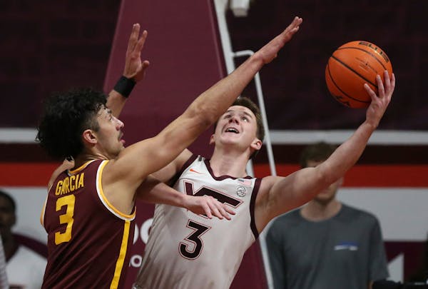 Virginia Tech’s Sean Pedulla scored from underneath the basket while being guarded by Gophers forward Dawson Garcia in the first half Monday.