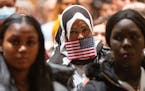 Muna Hassan stands during the National Anthem during a Naturalization Ceremony Tuesday, Nov. 29, 2022 at Saint Paul RiverCentre in St. Paul, Minn.