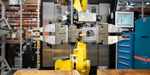 A robot at Graco moves finished cylinders from a CNC machine after testing them and restocks the machine with unfinished stock.