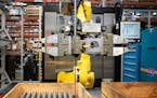 A robot at Graco moves finished cylinders from a CNC machine after testing them and restocks the machine with unfinished stock. ] GLEN STUBBE • glen