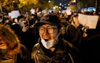 Protesters march along a street during a rally for the victims of a deadly fire as well as a protest against China’s harsh COVID-19 restrictions in 