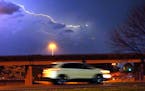 A vehicle races along a Jackson, Miss., street as lightning streaks across the sky, Tuesday evening, Nov. 29, 2022. Area residents were provided a lig
