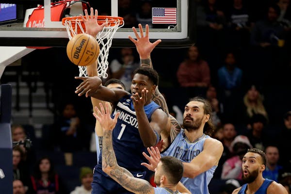 Timberwolves guard Anthony Edwards passed out of traffic and the defense of Grizzlies center Steven Adams in the first quarter at Target Center on Wed