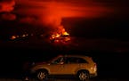 A man talks on a phone in his car alongside Saddle Road as the Mauna Loa volcano erupts Nov. 30, 2022, near Hilo, Hawaii.