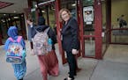 Interim Minneapolis Public Schools Superintendent Rochelle Cox, right, held open the front door for students heading into the first day of the school 