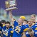 Anthony Rybinski did the honors with the Class 1A trophy as he and teammates celebrated Minneota’s eighth football state championship Friday.