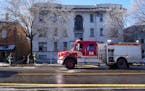 A member of the State Fire Marshal’s office and Minneapolis firefighters talked with an individual outside the scene of a building fire Saturday in 