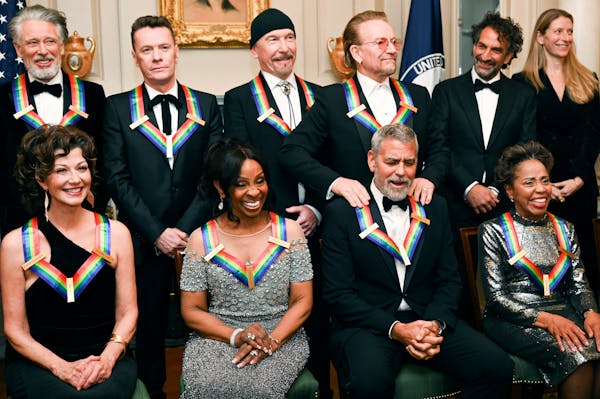 2022 Kennedy Center Honoree George Clooney, bottom second from right, reacts as he is given a shoulder rub from fellow 2022 Honoree Bono, top row thir