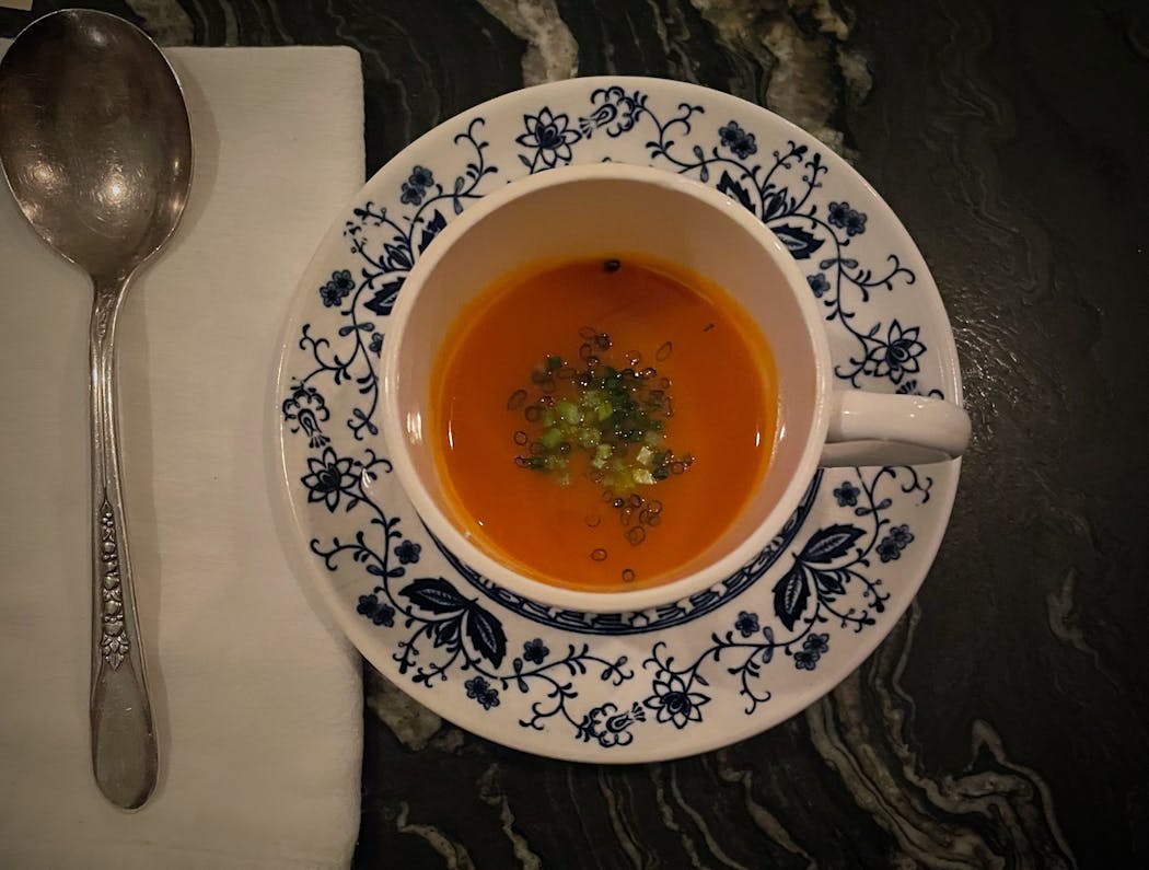 Carrot soup garnished with chives and green carrot tops at the bar at Myriel.