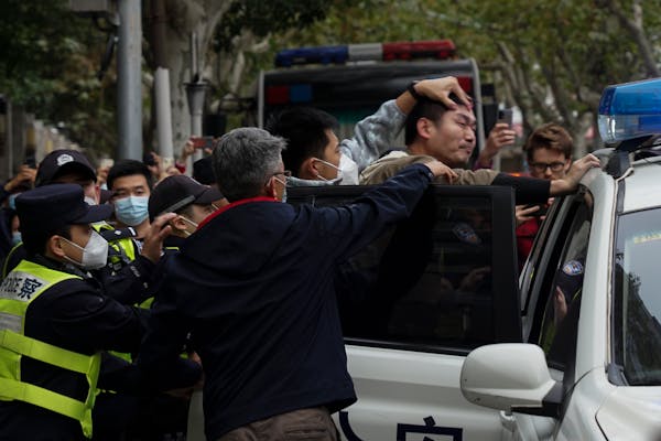 Officers force a protester into a police car during a demonstration in Shanghai, China on Nov. 27.