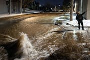 Ryan Merchant signaled to a co-worker a block away as they observed the water gushing downhill on 30th Avenue N. Monday night, Dec. 5, 2022 in Minneap