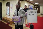 Buba Jaiteh, a Minneapolis resident affected by a water main freeze and break in the city, picked up bottled water distributed by the city at Farview 