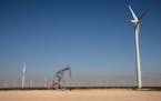 An oil pump jack operates near wind turbines at the Duke Energy Renewable’s Notrees Windpower project near Notrees, Texas, April 20, 2021. Worldwide