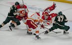 Wild and Flames players, including Calgary Flames goaltender Jacob Markstrom (25) pile up striving for the puck in the third period. The Minnesota Wil