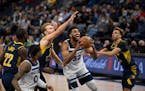 Minnesota Timberwolves center Karl-Anthony Towns (32) kept his eyes on the rim as he drove between Indiana Pacers forward Domantas Sabonis (11) and gu